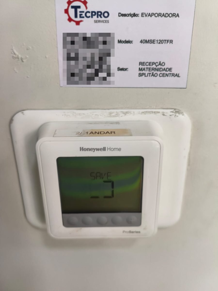 Etiqueta de identificação de ativo da Tecpro Services em evaporadora, ao lado do termostato do ambiente